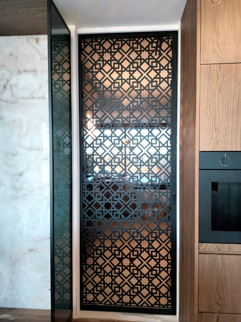 Puerta corredera interior con chapa calada a láser y vidrio laminado